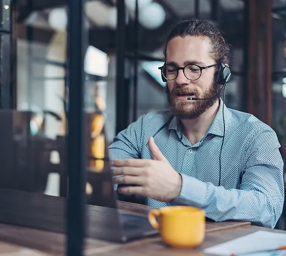 Image of a man wearing a headset while looking at a laptop screen, representing the service of website maintenance and support, indicating attentive customer assistance and technical troubleshooting